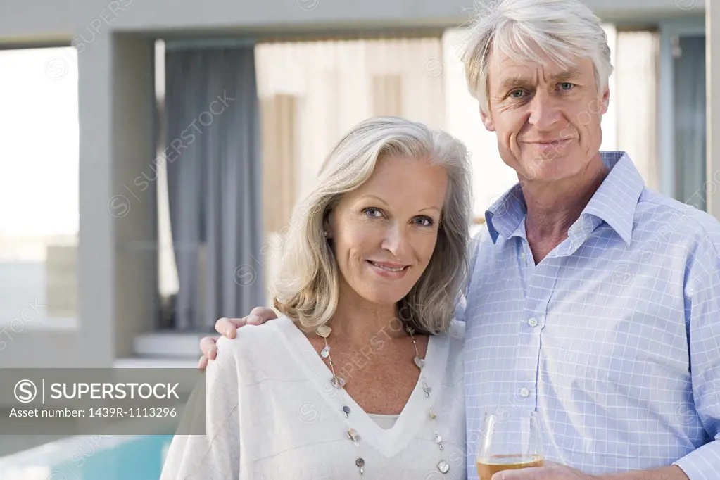 Middle aged couple standing outside house