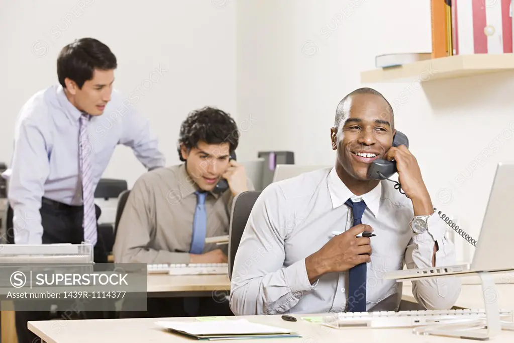Three male office workers at their desks