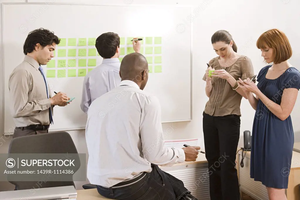 Office workers writing ideas on adhesive notes