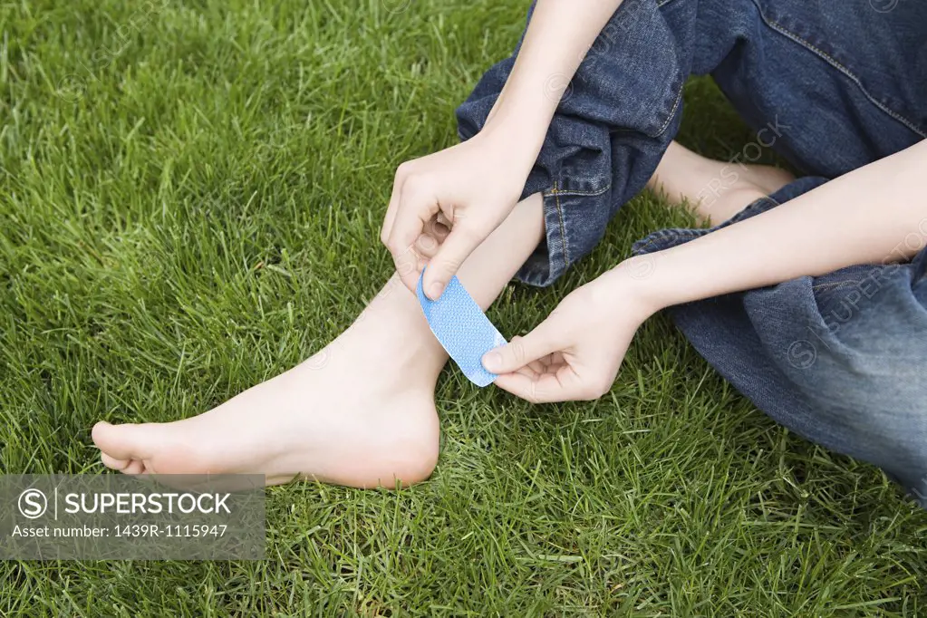 Child putting plaster on ankle