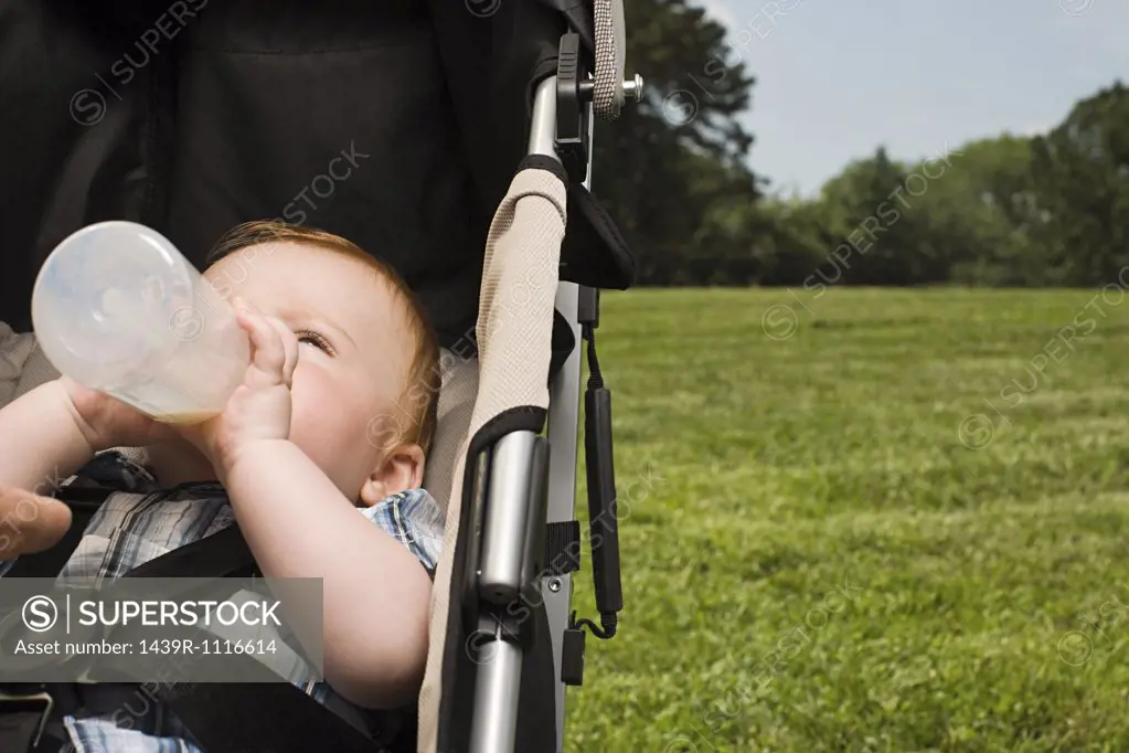Baby in push chair with bottle