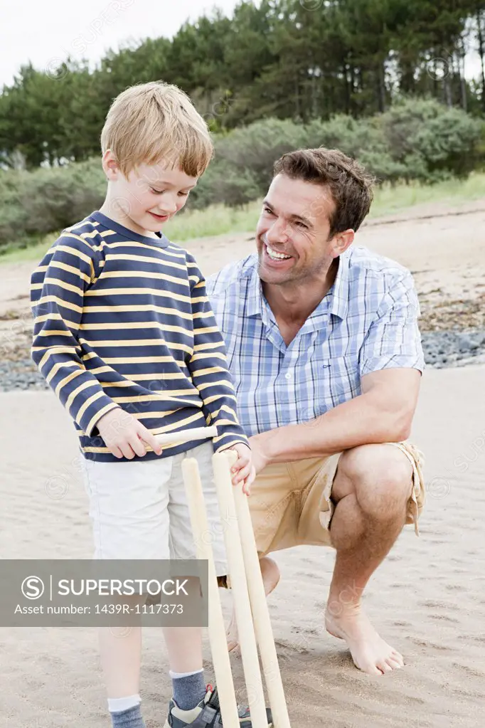 Father and son on beach with cricket stumps