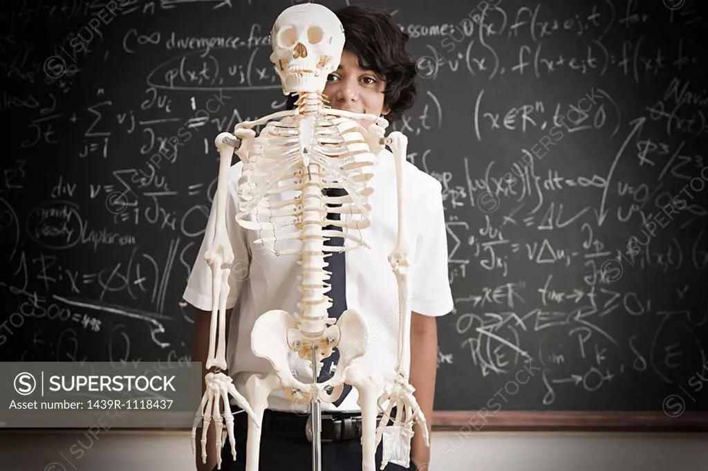 Boy and skeleton in front of blackboard