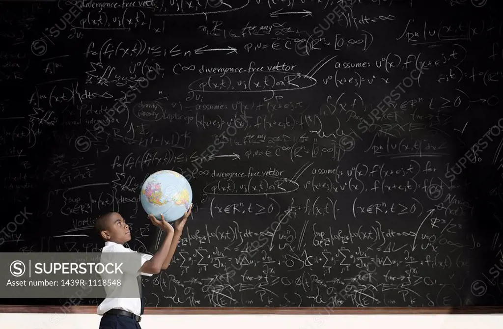 Boy with globe in front of blackboard