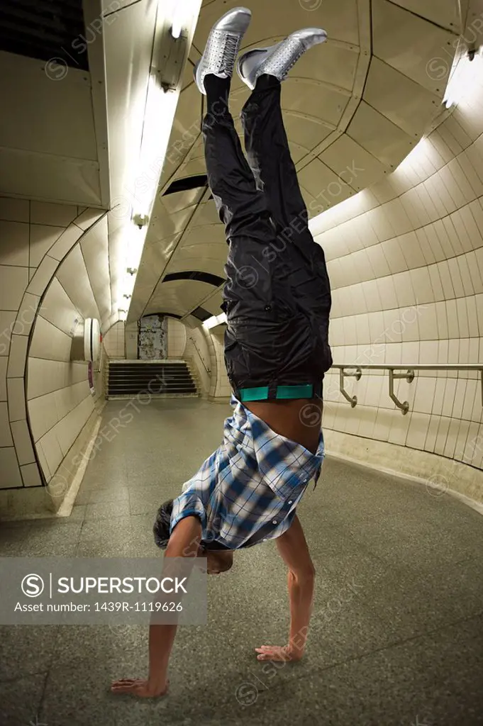 A man doing a handstand on the underground