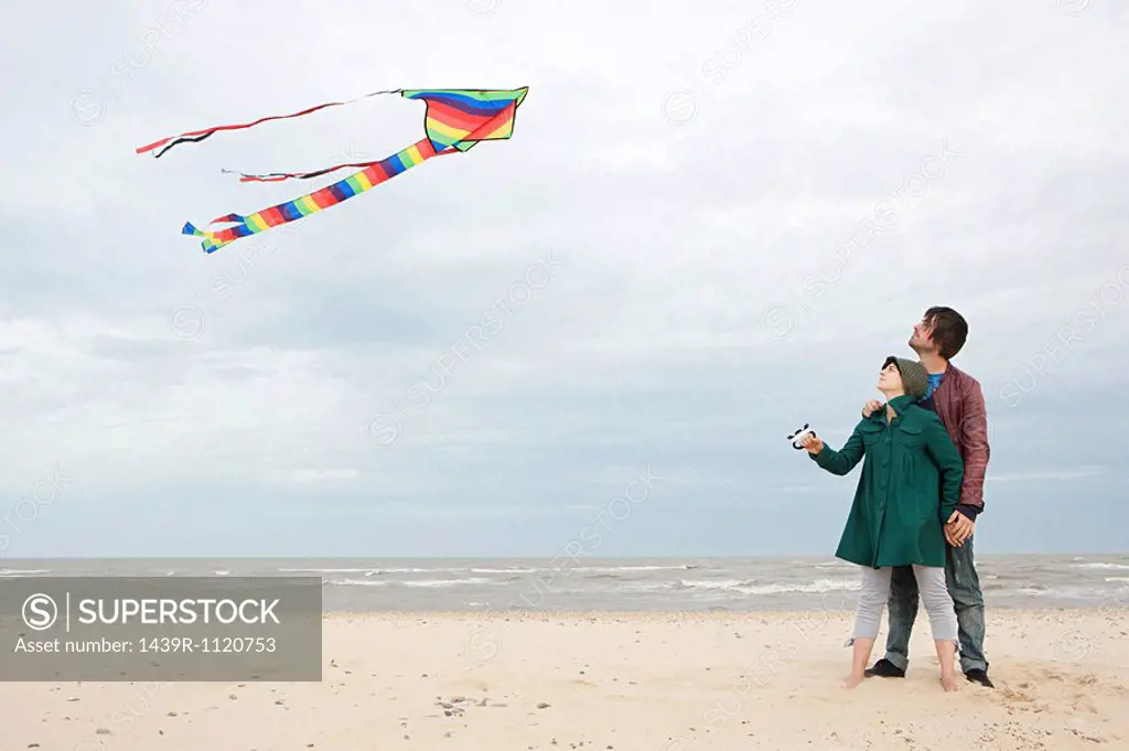 Young couple with kite by the sea