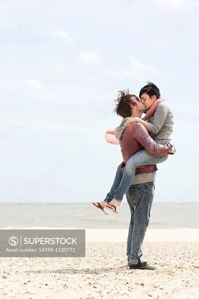 Man carrying girlfriend by the sea
