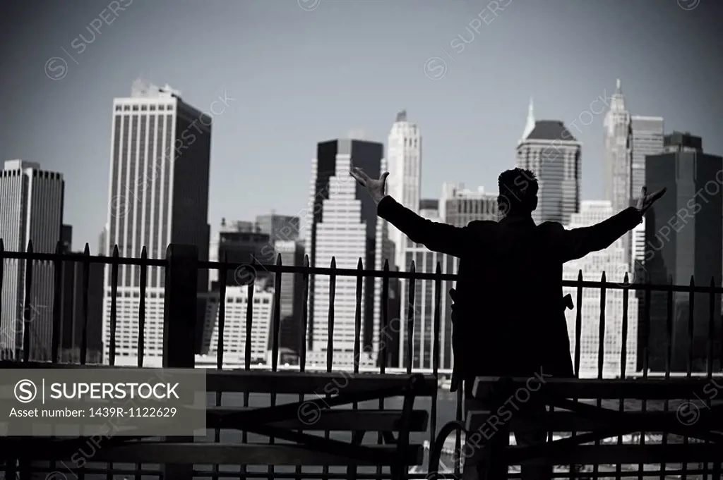 Man with arms open and view of lower manhattan