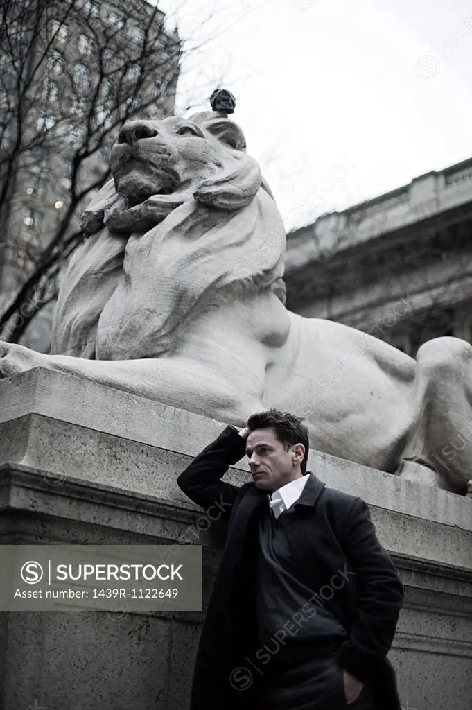 Man by lion statue at new york public library