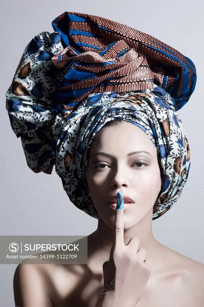 Young woman wearing head tie with finger on lips