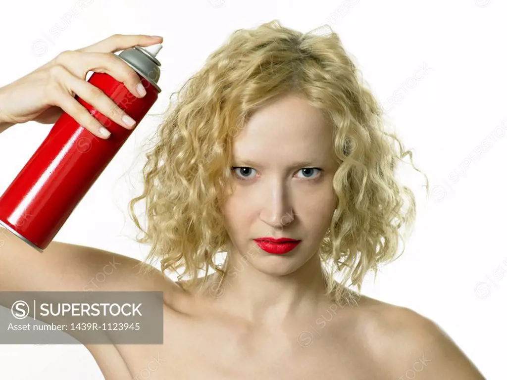 Young woman using hairspray