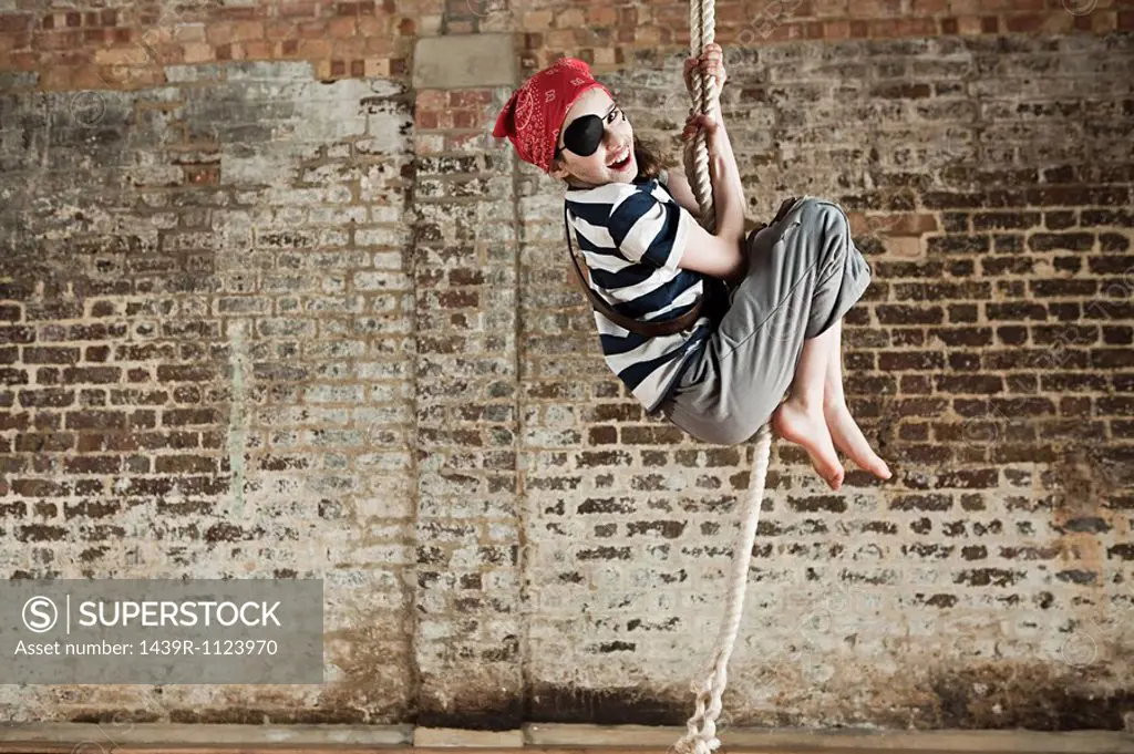 Young girl dressed up as pirate, climbing rope