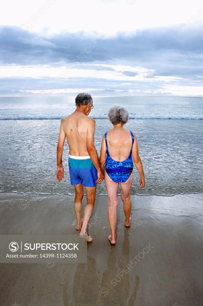 A mature couple going for a swim on the beach