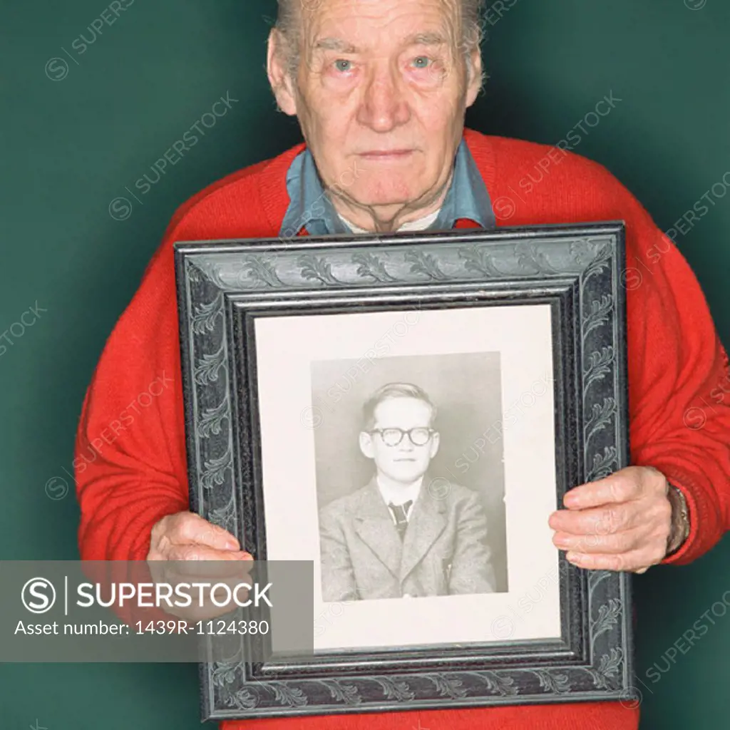 Senior man holding a portrait of a young man