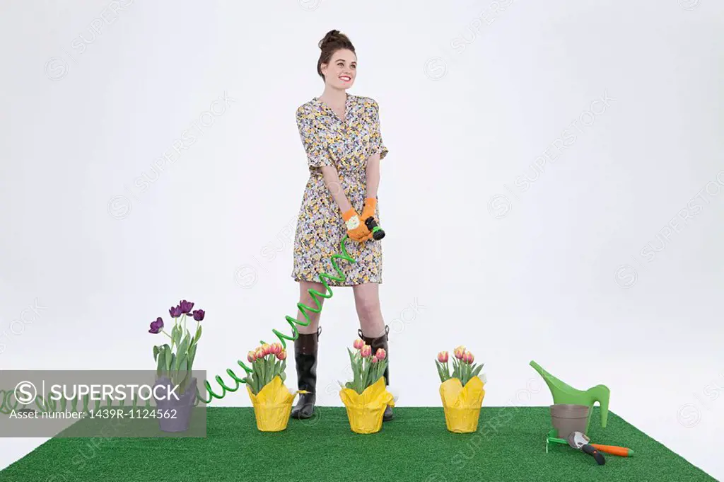 Woman with hose and flowers on artificial turf