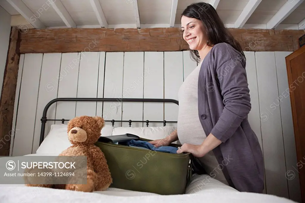 Expectant mother packing suitcase
