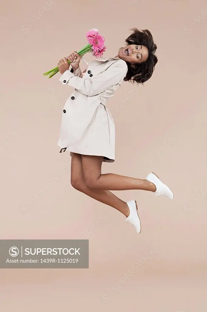 Young woman holding flowers and jumping