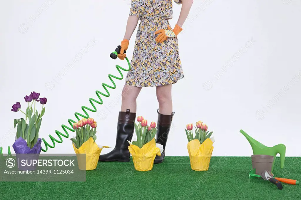 Woman with hose and flowers on artificial turf