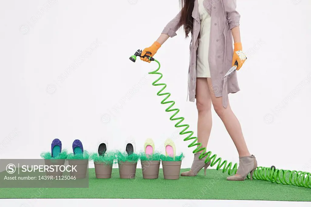 Woman with hosepipe and shoes in flower pots