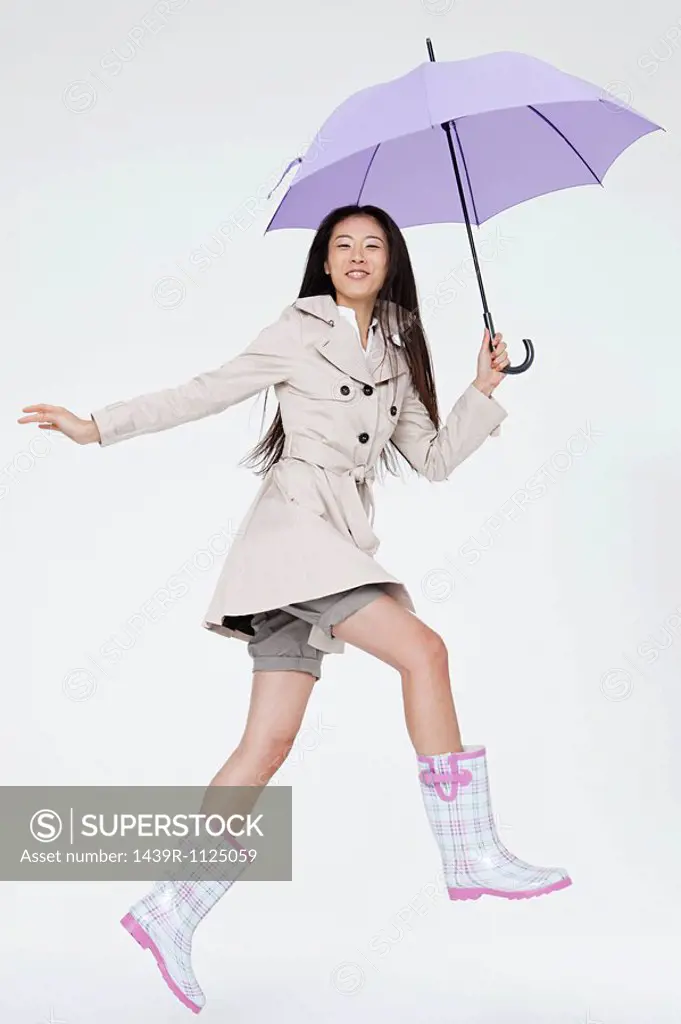 Woman holding umbrella and jumping