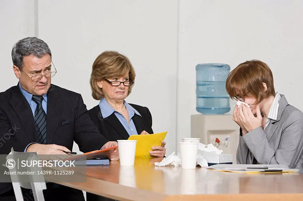 Businesswoman blowing nose in office