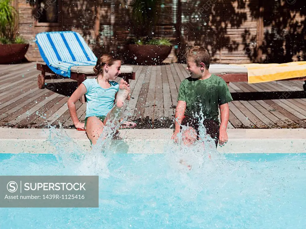 Boy and girl splashing in swimming pool