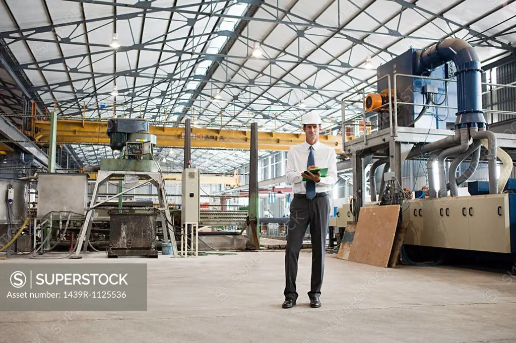 Mature man with clipboard in factory