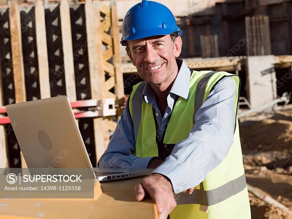 Mature man with laptop on construction site