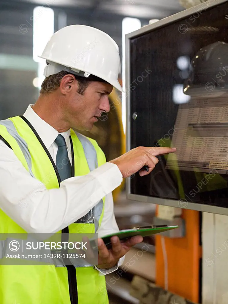 Mature man inspecting factory equipment