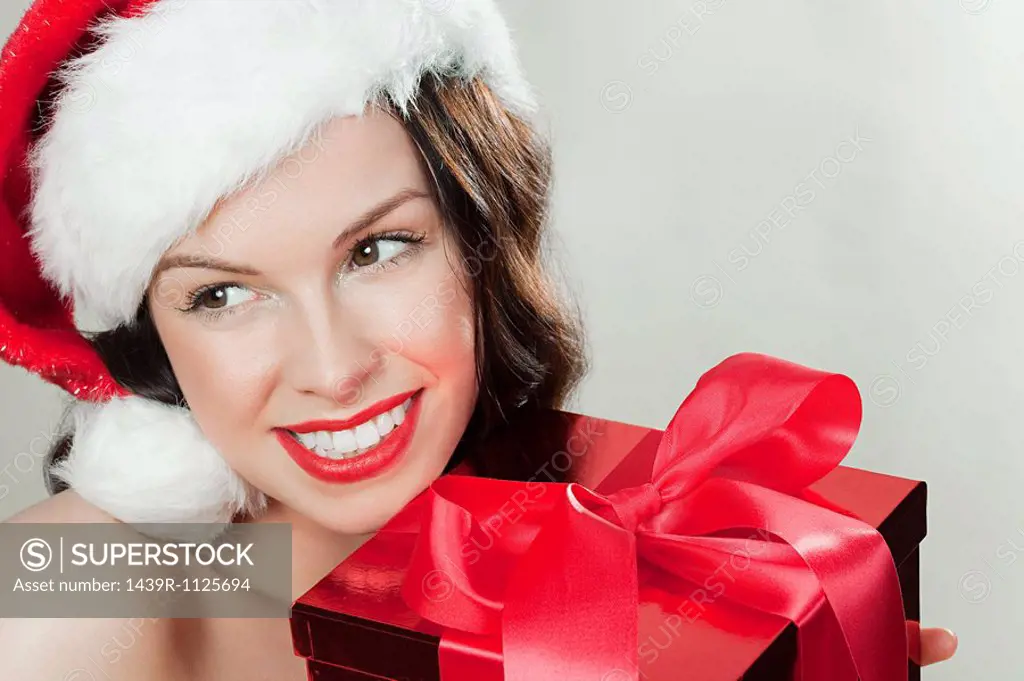 Young brunette woman wearing Santa hat with Christmas present