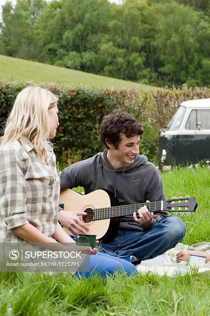 Young man playing guitar to girlfriend