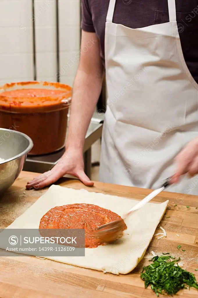 Male chef making pizza in commercial kitchen
