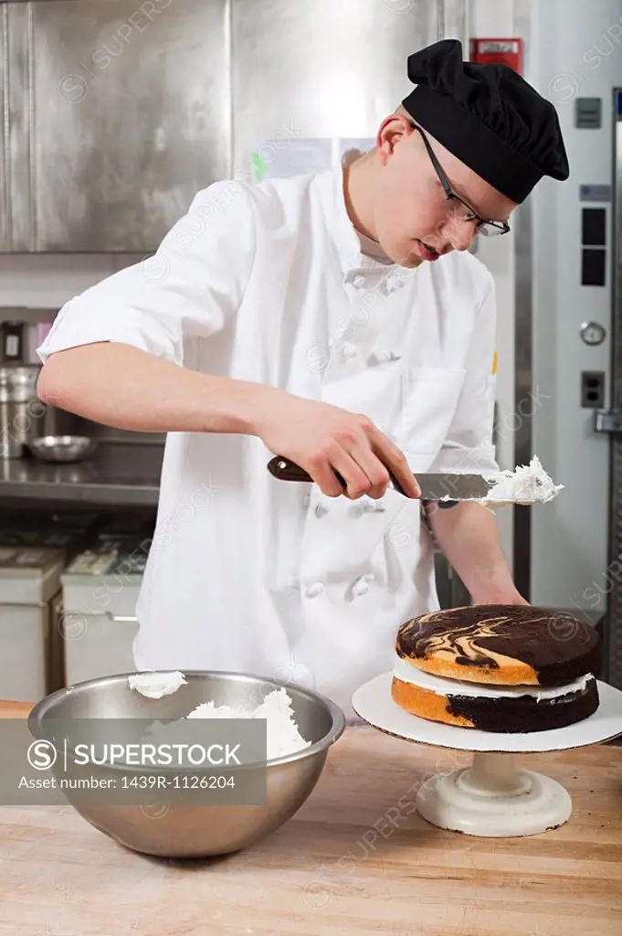 Male chef icing a cake in commercial kitchen