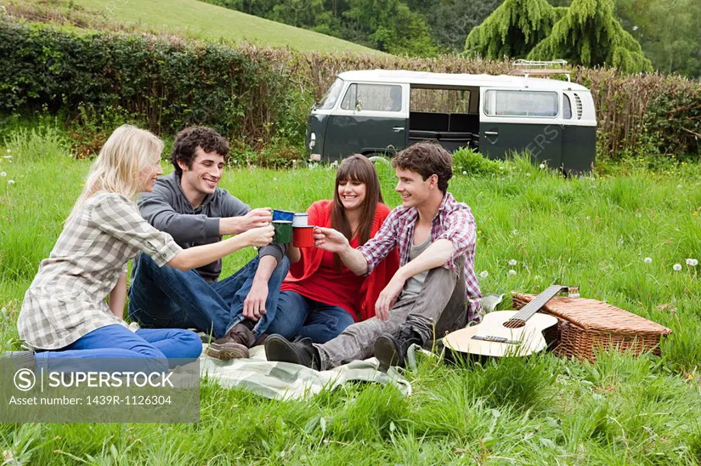 Friends toasting with mugs outdoors