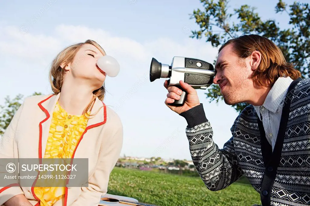 Man filming girlfriend blowing bubble gum
