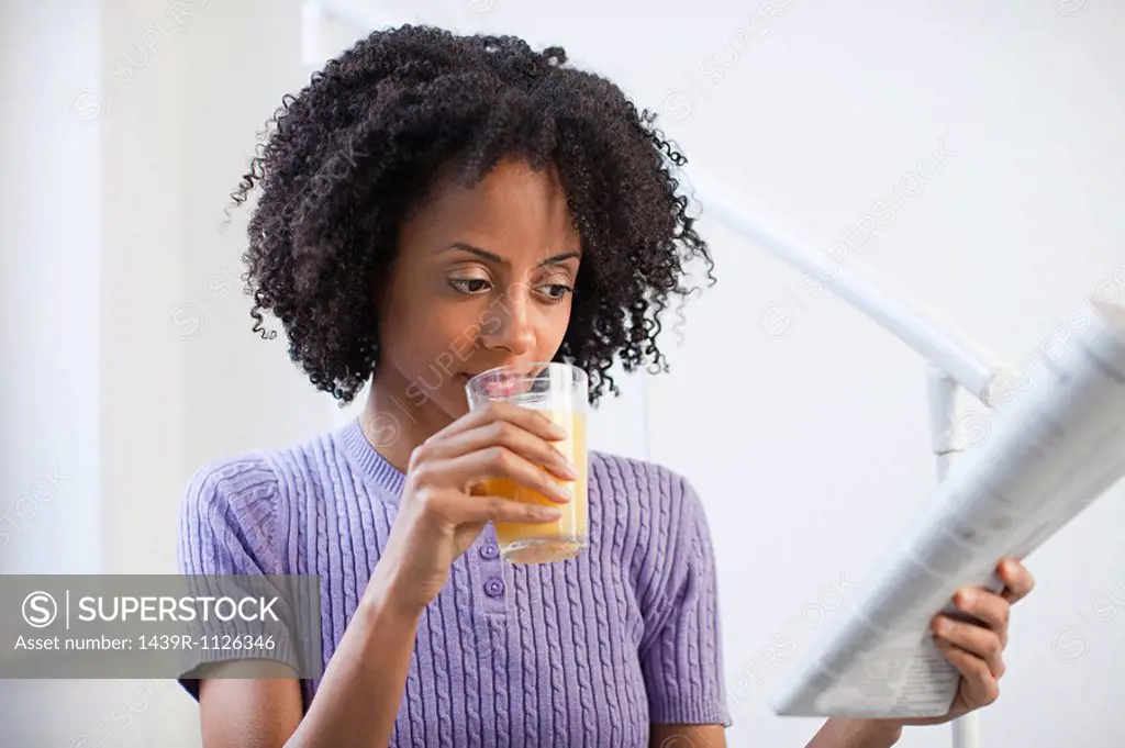 Woman with glass of juice and newspaper