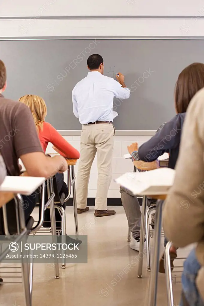 High school teacher using white board in classroom
