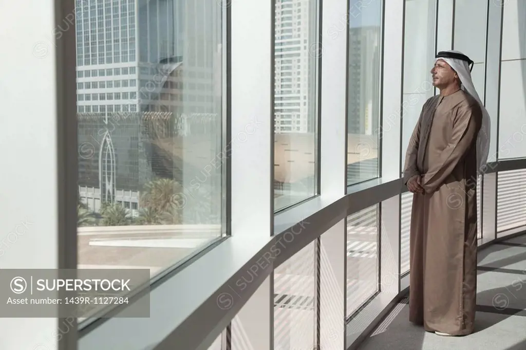 Middle eastern businessman looking out of office window