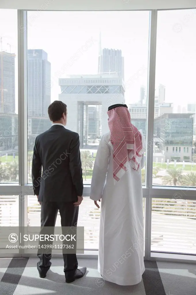 Western and middle eastern businessmen by window of dubai office