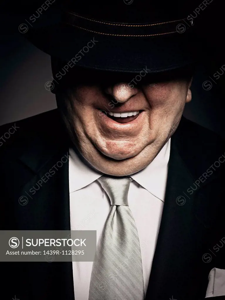 Studio portrait of gangster with hat covering face