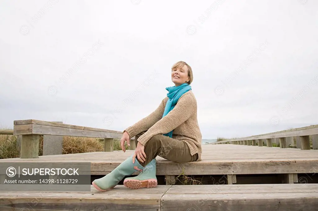 Woman sitting on walkway at the coast