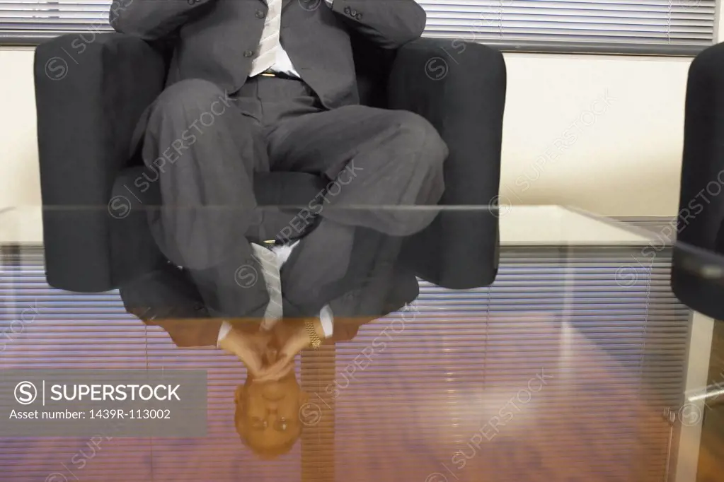 Businessman reflected in glass table