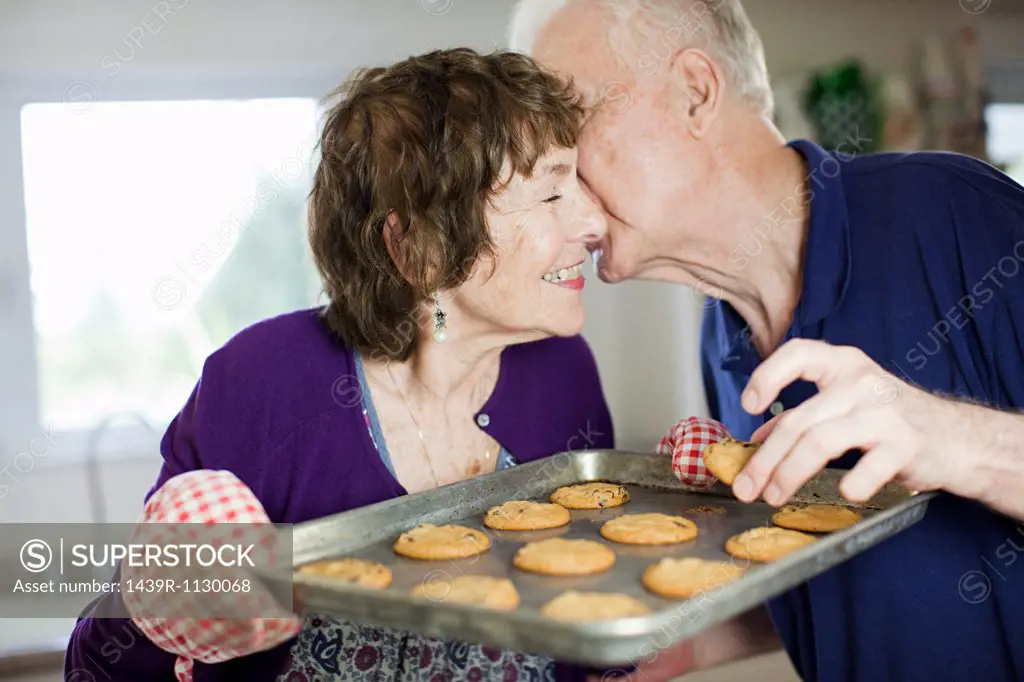 Senior couple kissing with home baked cookies