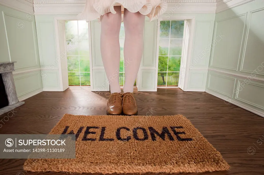 Legs of a woman and welcome mat in small room