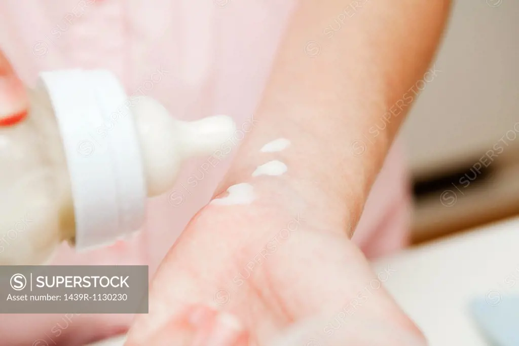 Mother testing baby milk on wrist