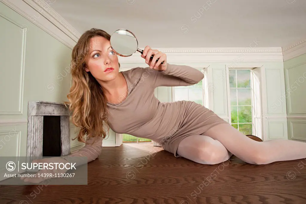 Young woman in small room with magnifying glass