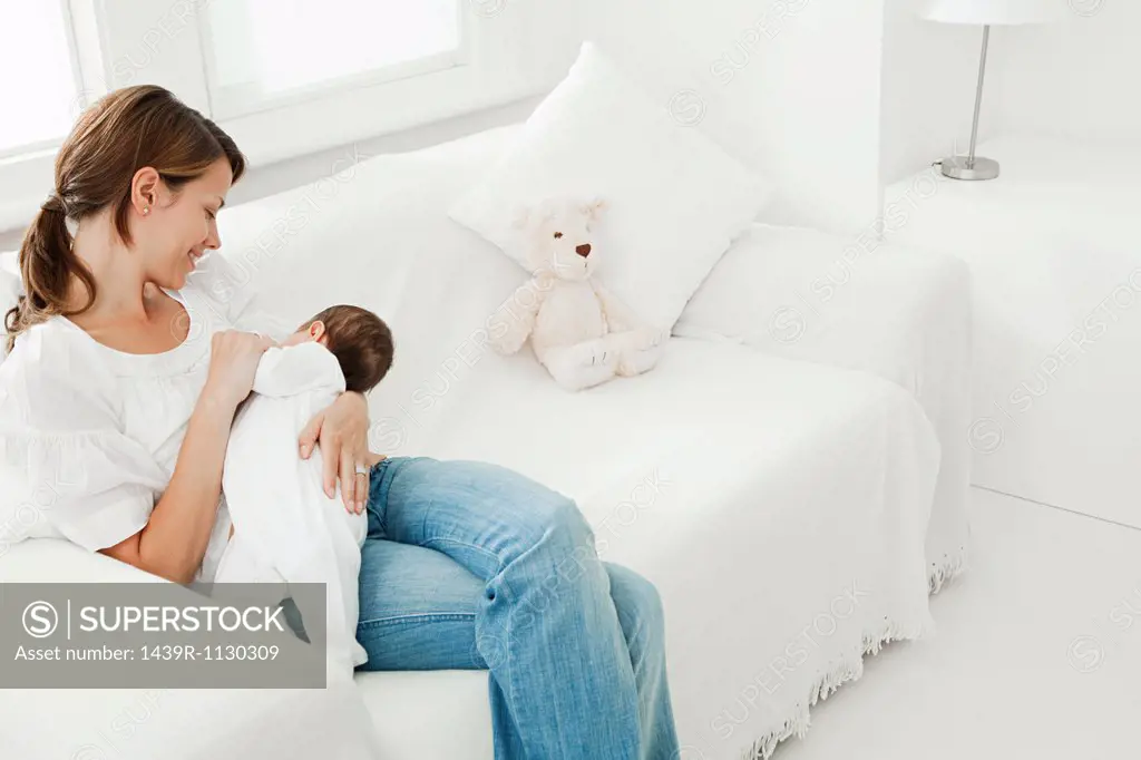 Mother breast feeding baby on sofa