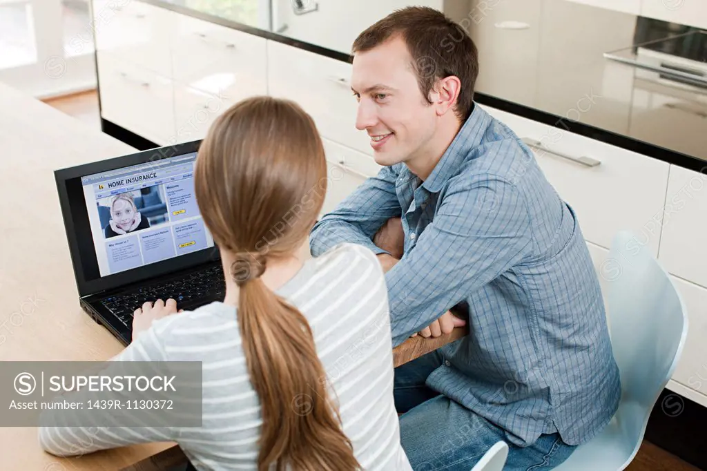 Young couple looking at insurance on laptop