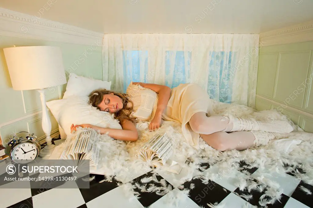Young woman sleeping amongst pillow feathers in small room