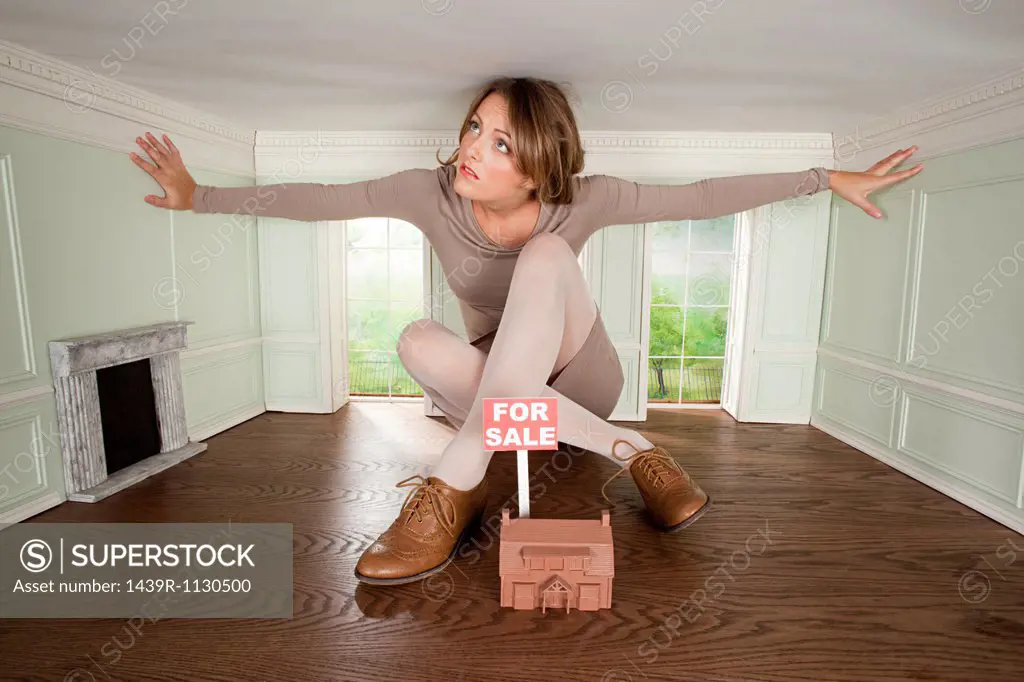 Young woman in small house with model of house for sale